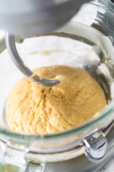 Mixing ingredients in kitchen mixer to bake mini Easter bread kulich.