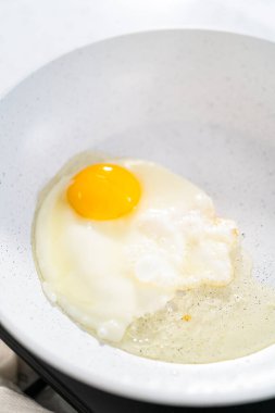 Yumurta ve filizli sandviç yapmak için tavada yumurta kızartıyorum..