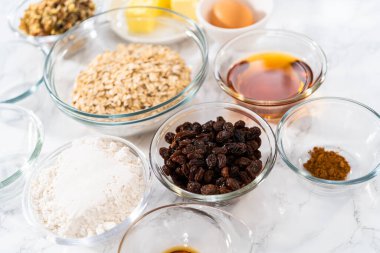 Yumuşak yulaf ezmesi üzümlü cevizli kurabiye pişirmek için cam karışımında ölçülmüş malzemeler..