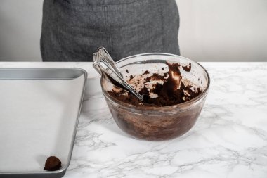 Naneli beyaz çikolatalı kurabiyeler pişirmek için parşömen kağıdıyla kaplı küçük bir hamur kepçesiyle kurabiye hamuru pişirmek..