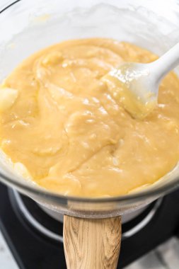 Beyaz çikolata parçacıkları ve diğer malzemeleri kaynamış suyun üzerine karıştırıp beyaz çikolatalı fındıklı fındıklı çikolata hazırlıyorum..