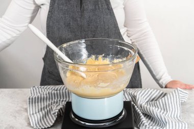 Eriyen beyaz çikolata parçacıkları ve diğer malzemeler kaynamış suyun üzerinde karışıp kızılcık fıstıklı şekerleme hazırlıyor..