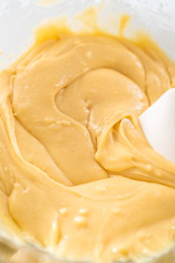 Eriyen beyaz çikolata parçacıkları ve diğer malzemeler kaynamış suyun üzerinde karışıp kızılcık fıstıklı şekerleme hazırlıyor..