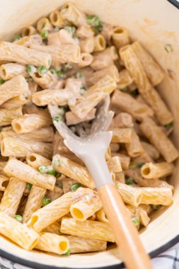 Alfredo soslu tavuk pişirmek için mayalı bir fırının içindekileri karıştırıyorum..