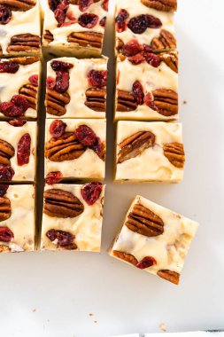 Beyaz çikolatalı fındıklı fındıklı şekerlemeyi beyaz bir kesme tahtasında küçük parçalara ayırmak..