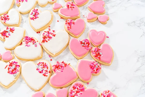 ハート型の砂糖クッキーにピンクと白のロイヤルアイシングをバレンタインデーに飾る — ストック写真
