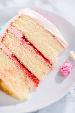 Deniz kızı temalı 3 katlı vanilyalı pasta dilimi. Çikolatalı deniz kızı kuyruğu ve beyaz tabakta deniz kabukları..