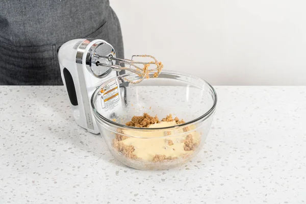 Mixing ingredients with a hand mixer in a large mixing bowl to bake dulce de leche cupcakes.