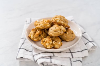 Beyaz bir tabakta taze pişmiş beyaz çikolatalı macadamia fındığı..