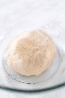 Tarçınlı tatlı pizzası hazırlamak için cam bir kasede pizza hamuru yetiştiriyorum..