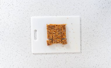 Düz yatıyordu. Beyaz bir kesme tahtasında balkabağı baharatlı şekerlemeyi kare parçalara ayırmak..