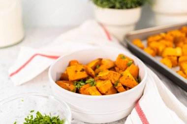 Beyaz seramik bir kasede fırında tatlı patates servis ediyorum..