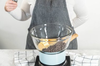 Eriyen beyaz çikolata parçaları ve diğer malzemeler kaynamış suyun üzerine karıştırıp çubuk şekerleme hazırlıyor..