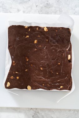 Parşömenle kaplı kare bir peynirli kek tavasından çikolatalı macadamia şekerlemesi çıkarıyorum..