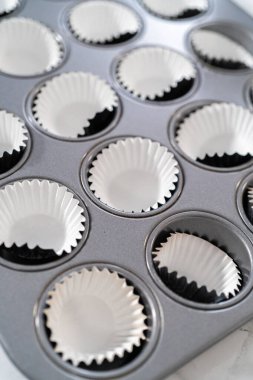 Scooping cupcake batter with dough scoop into a baking pan with liners to bake American flag mini cupcakes.