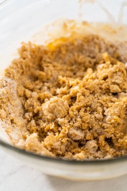 Islak ve kuru malzemelerle karıştırılmış cam bir kabın içinde çırpılmış beyaz çikolatalı makadamia fındığı..