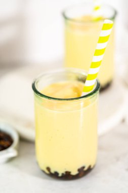 Taze yapılmış mango boba smoothie. Kağıt kamışla içme bardağında..