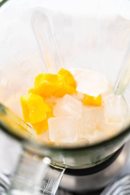 Mutfak blendırında mango boba smoothie hazırlamak için malzemeler karıştırılıyor.