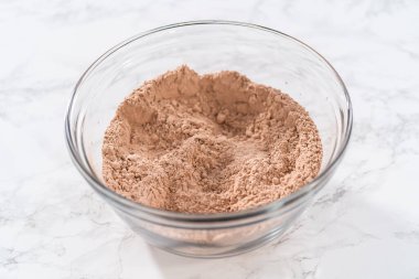 Büyük bir bardakta ıslak malzemeler karıştırarak kırmızı kadife kekler ve beyaz çikolatalı ganache kreması pişiriyorum..