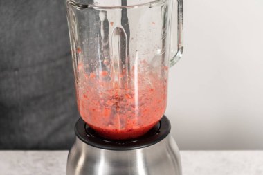 Çilekli kremayı hazırlamak için mutfak blendırında taze çilek harmanlıyorum..