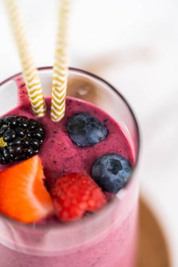 Taze böğürtlen ve kağıt kamışla süslenmiş taze meyve püresi..