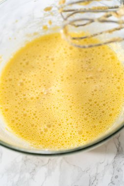 Malzemeleri karıştırıcı ile karıştırarak büyük bir karıştırma kabında yumurta likörü pişirmek..