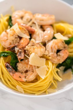 Beyaz seramik kaselerde ıspanaklı sarımsaklı karides makarnası servis ediyorum..