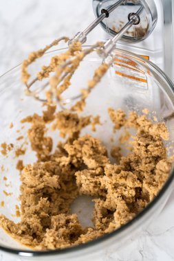 Büyük bir bardakta ıslak malzemeler karıştırarak kırmızı kadife kekler ve beyaz çikolatalı ganache kreması pişiriyorum..