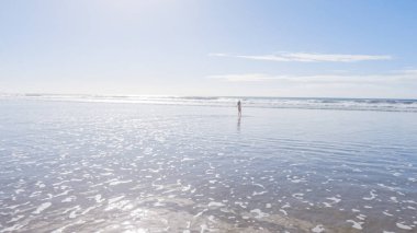 Küçük kız, soğuğa göğüs geriyor, kışın sahilde mayosuyla koşuyor..