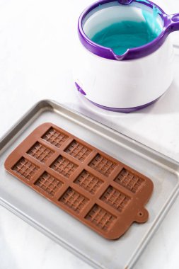 Çikolata kalıplarını erimiş çikolatayla doldurarak küçük denizkızı çikolatalarını hazırlıyorum..