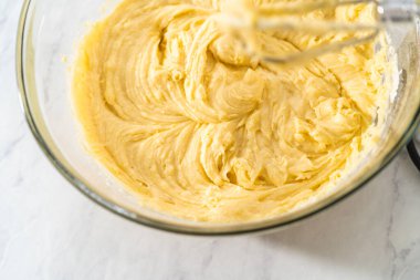 Limonlu yaban mersinli kek yapmak için büyük bir bardakta karıştırma malzemesi..