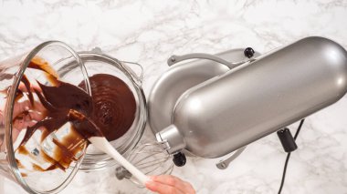 Düz yatıyordu. Adım adım. Elektrikli mutfak mikseriyle çikolatalı ganache çırpmak..