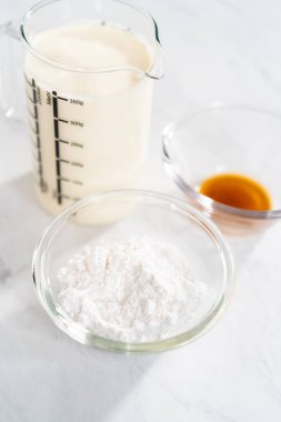 Ev yapımı krem şanti hazırlamak için cam karıştırma kabında ölçülmüş malzemeler..