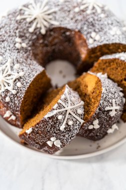 Dilimlenmiş zencefilli kek karamel dolgulu, kremalı pasta ve kek tabağında toz şeker..