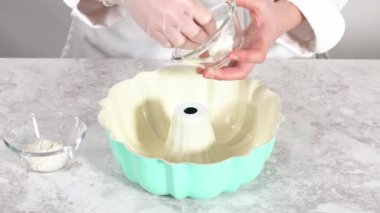 Time lapse. Greasing bundt cake pan with vegetable shortening and flour to bake funfettti bundt cake.