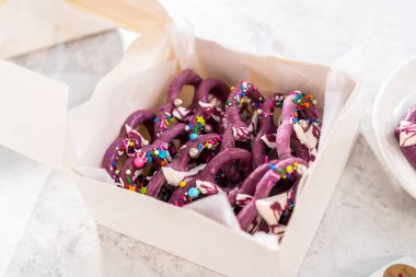 Packaging homemade mermaid pretzel twists into a white paper box.