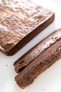 Çikolatalı fıstık ezmeli şekerlemeyi beyaz bir kesme tahtasında küçük parçalara ayırmak..