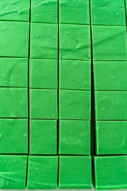 Büyük bir mutfak bıçağıyla yeşil şekerlemeyi beyaz bir kesme tahtasında kare parçalara ayırmak..