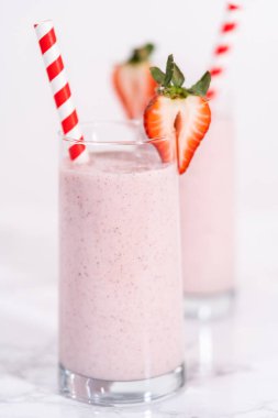 Taze taze çilek ve kağıt kamışla süslenmiş sağlıklı bir kahvaltı muzlu smoothie..