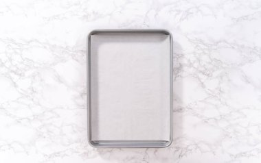 Düz yatıyordu. Parşömen kağıdıyla kaplı bir kabın üzerinde tarçınlı tatlı pizzası hazırlıyorum..