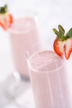 Taze taze çilek ve kağıt kamışla süslenmiş sağlıklı bir kahvaltı muzlu smoothie..