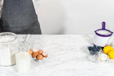 Cam bir kasenin içindeki bileşenleri birleştirmek, bir çırpıcıyla karıştırmak, limonlu-yabanmersinli kek hazırlamak..