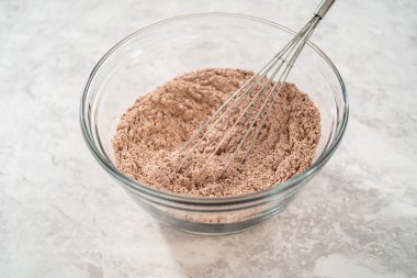 Çikolatalı kurabiyeleri naneli cipsle karıştırmak için büyük bir bardaktaki malzemeleri karıştırıyorum..