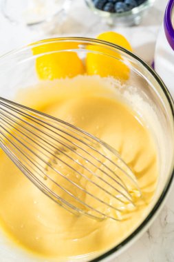 Cam bir kasenin içindeki bileşenleri birleştirmek, bir çırpıcıyla karıştırmak, limonlu-yabanmersinli kek hazırlamak..