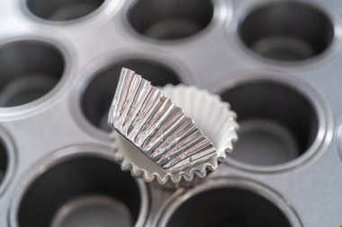 Scooping cupcake batter with dough scoop into a baking pan with liners to bake American flag mini cupcakes.