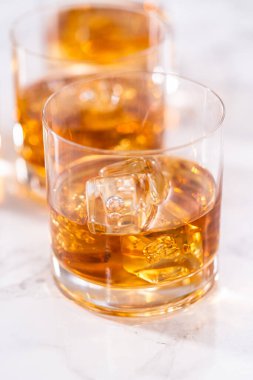 Buzlu viski, viski bardağında, beyaz mermer yüzeyde..