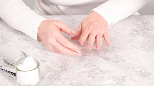 Woman finishing her manicure at home with simple manicure tools. Cutting out cuticles around the nails.
