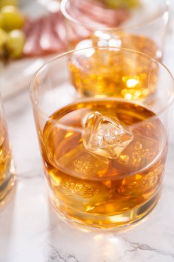 Buzlu viski, viski bardağında, beyaz mermer yüzeyde..