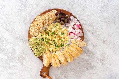 Düz yatıyordu. Sebzeli tereyağı tahtası ve tahta kesme tahtasında ekmek..