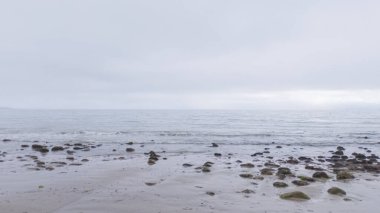 Kaliforniya, Miramar Sahili kıyılarında yürürken bulutlu kış gökyüzü sakin ve yansıtıcı bir atmosfer yaratır..